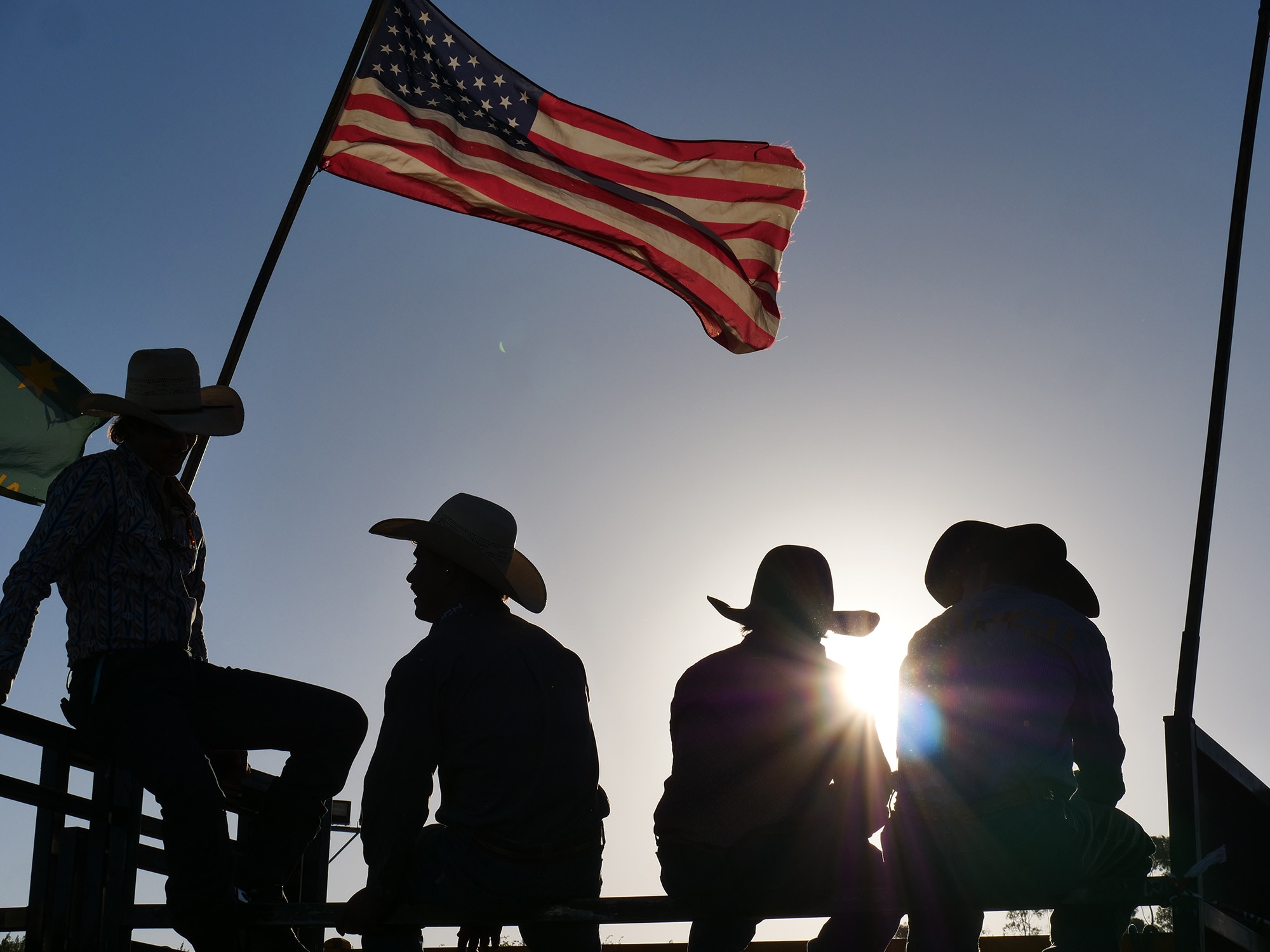 A backlit photo of people near a flag