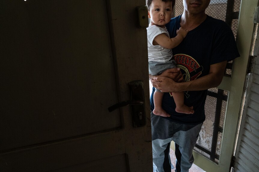 A man holds his child on his hip. 