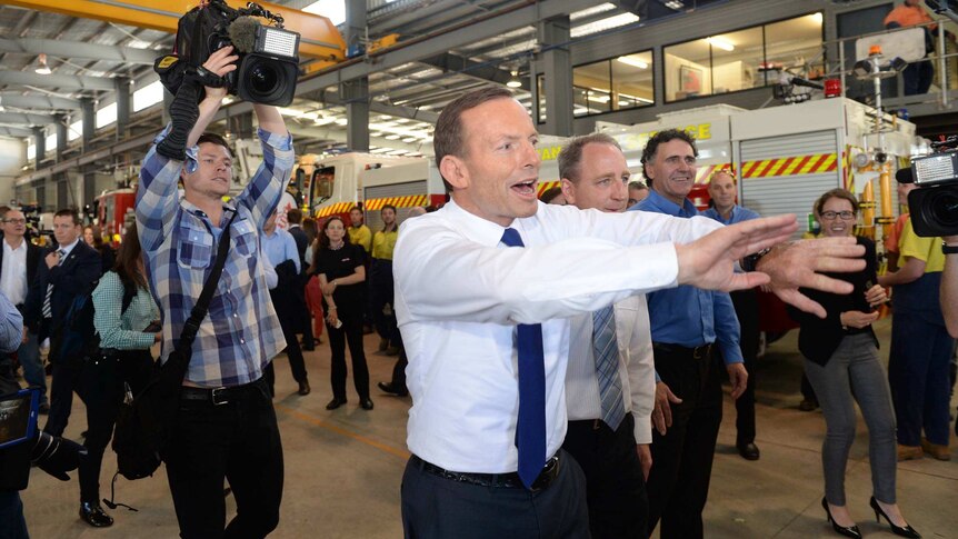 Tony Abbott moves media out of the way during a visit to a vehicle manufacturer