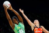 Jhaniele Fowler looks to the side with her hands high above her head, catching the ball