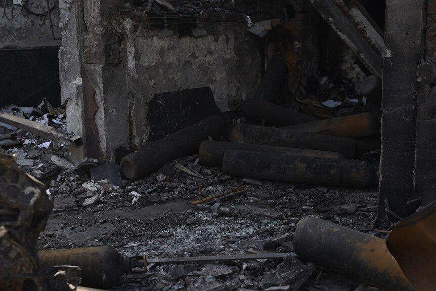 cylinders charred on the outside amidst rubble of burned building