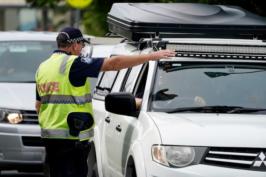 A police officer pointing inside a car