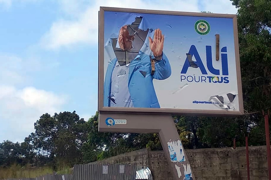 A defaced billboard with the face of Ali Bongo smashed in 