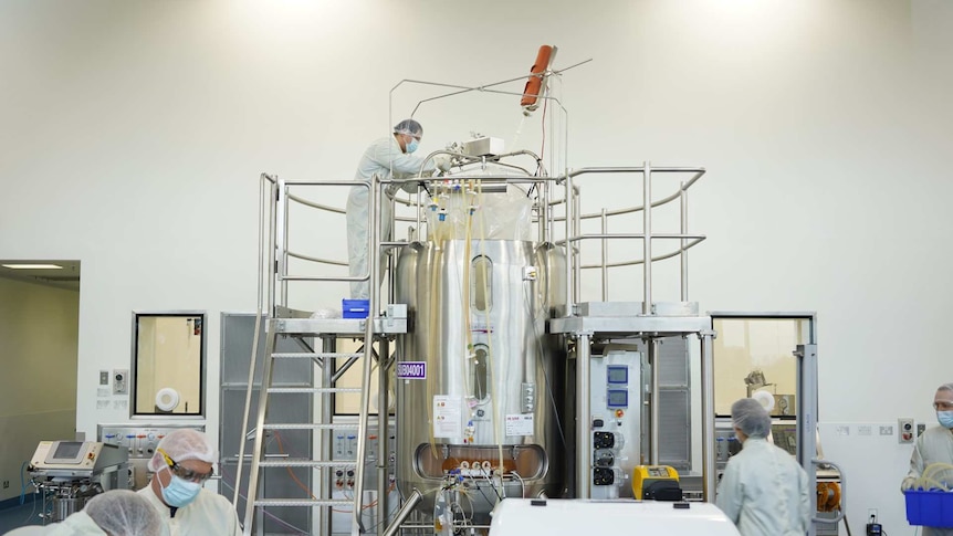 People in white lab coats and hairnets in a room with stainless steel laboratory equipment