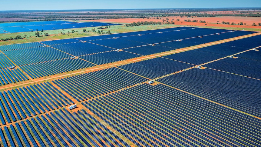 aerial shot of thousands of solar panels on a red dirt plain