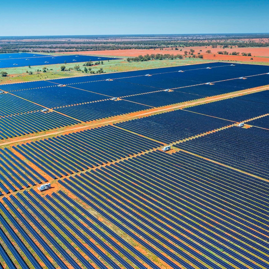 aerial shot of thousands of solar panels on a red dirt plain