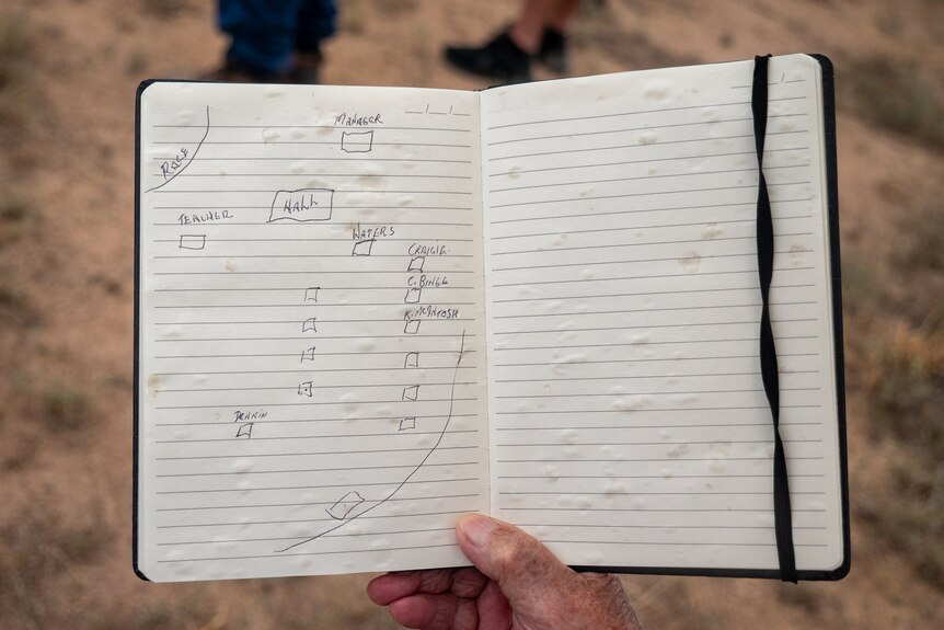 A hand holding a notebook with a map drawn in it, Old Toomelah, New South Wales, March 2024.
