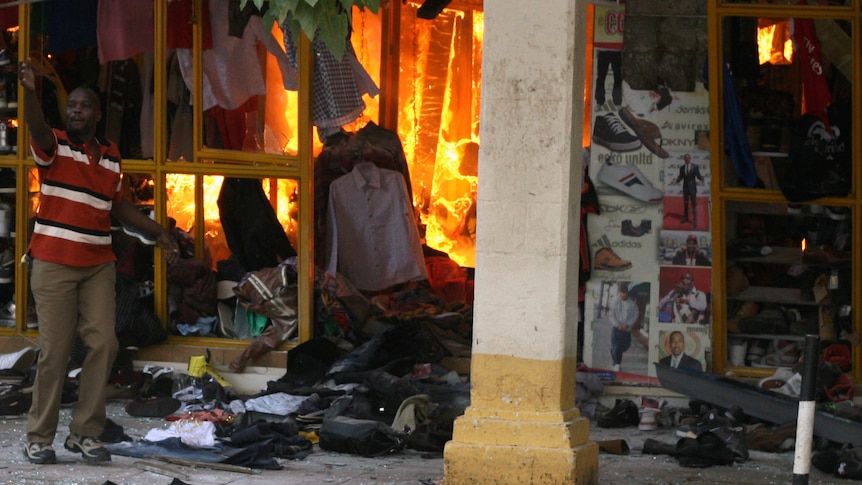 A civilian attempts to extinguish fire inside a clothing shop after an explosion in a shopping centre in Nairobi.