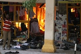A man tries to extinguish a fire inside a clothing shop after the explosion.