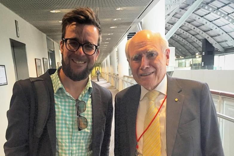 Man standing next to John Howard smiling.