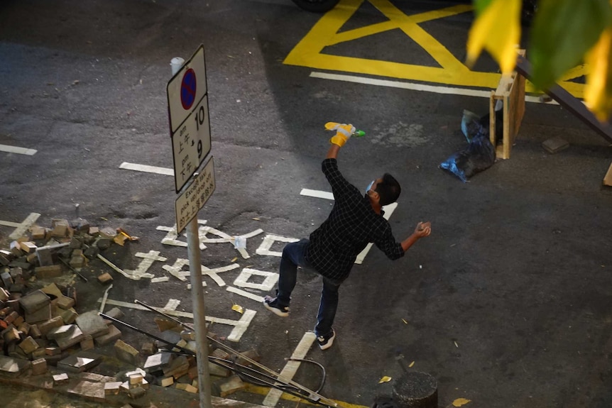 A man on a street throws a brick.