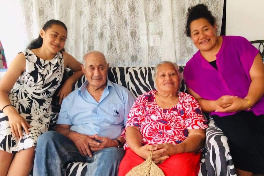 A group of four colourfully dressed people on a couch.