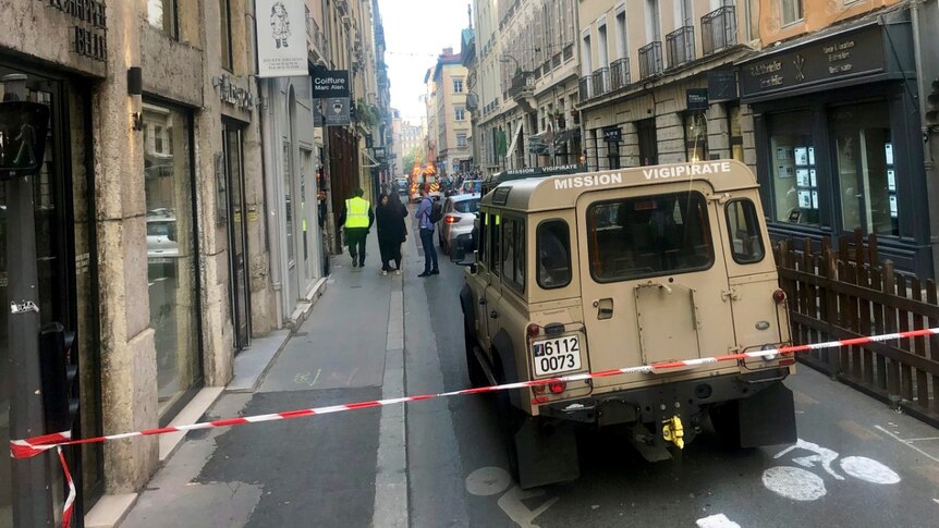 A French anti-terror vehicle is shown parked in a narrow Lyon street that is cordoned off with red and white tape.