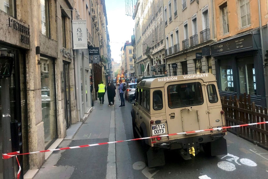 A French anti-terror vehicle is shown parked in a narrow Lyon street that is cordoned off with red and white tape.