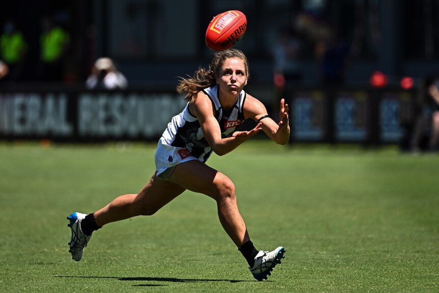 Mikala Cann stretches for a mark during an AFLW match.