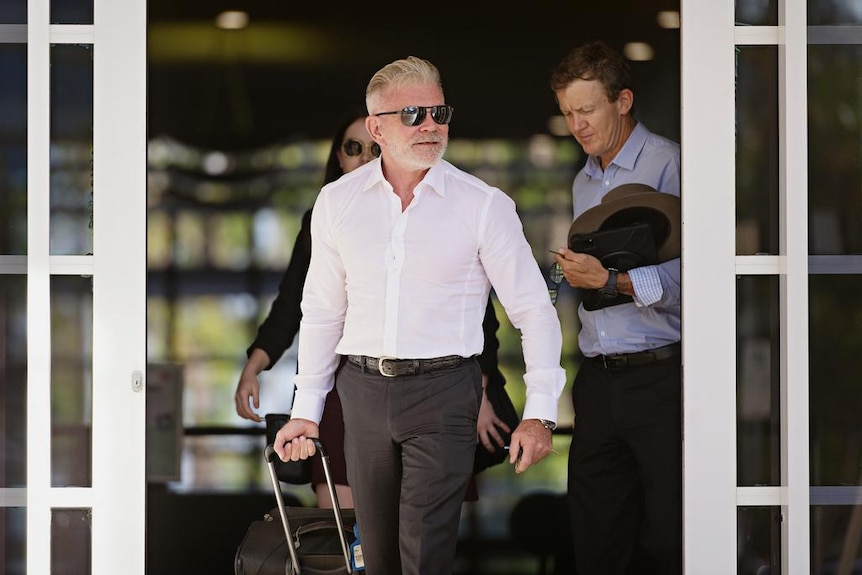 Two men wearing suits exit a court house in Darwin.