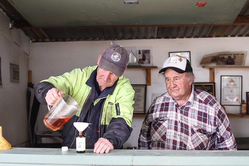 Robbie Collins with volunteer Warren pouring the eucalyptus oil into a bottle.