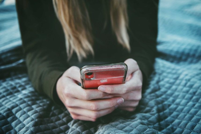 A close up of a girl's hands looking on a phone.