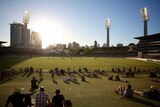 A wide shot of the WACA Ground with spectators sitting on grass watching a ODI between Australia and South Africa under the sun.