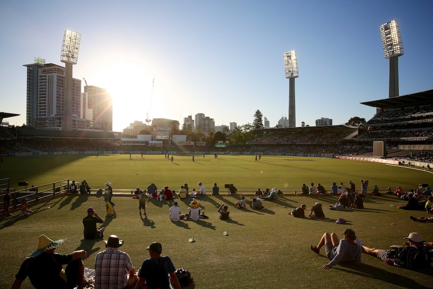 A wide shot of the WACA Ground with spectators sitting on grass watching a ODI between Australia and South Africa under the sun.