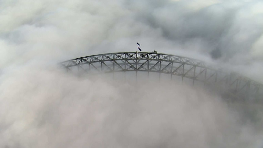 The top of a large metal structure poking through the clouds