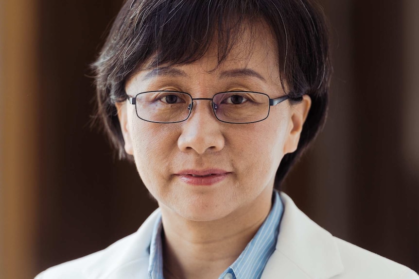 A headshot of a woman in a blue shirt and cream jacket.