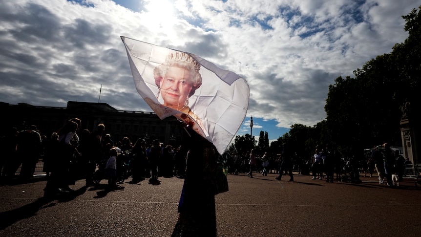 A flag with an image of Queen Elizabeth II is waved outside the palace