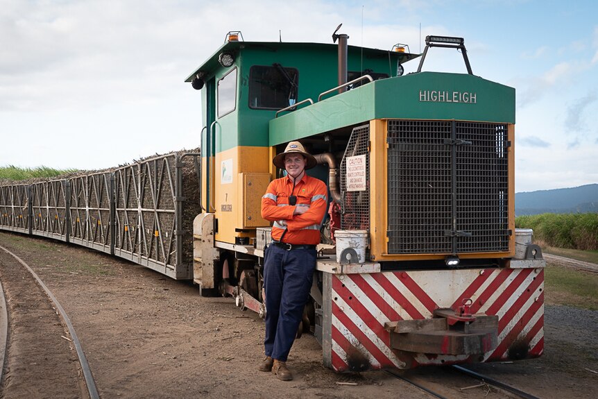 man leans on cane train with load of sugar cane in background