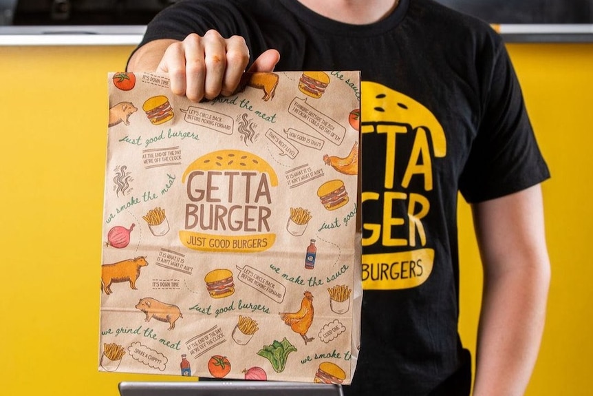 A man holds a burger bag