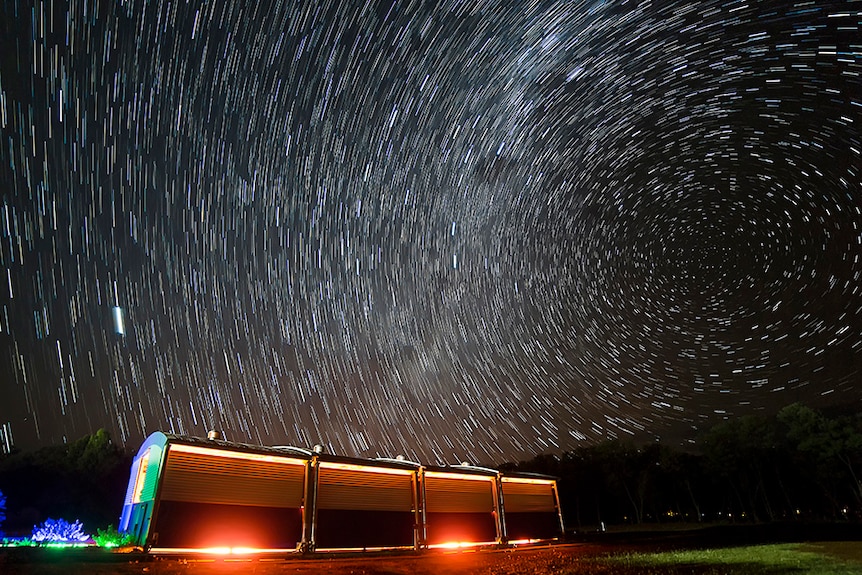 A lit up building beneath a night sky filled with stars.