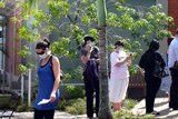 Patients wearing face masks wait to see a doctor outside a swine flu medical clinic in Cairns.