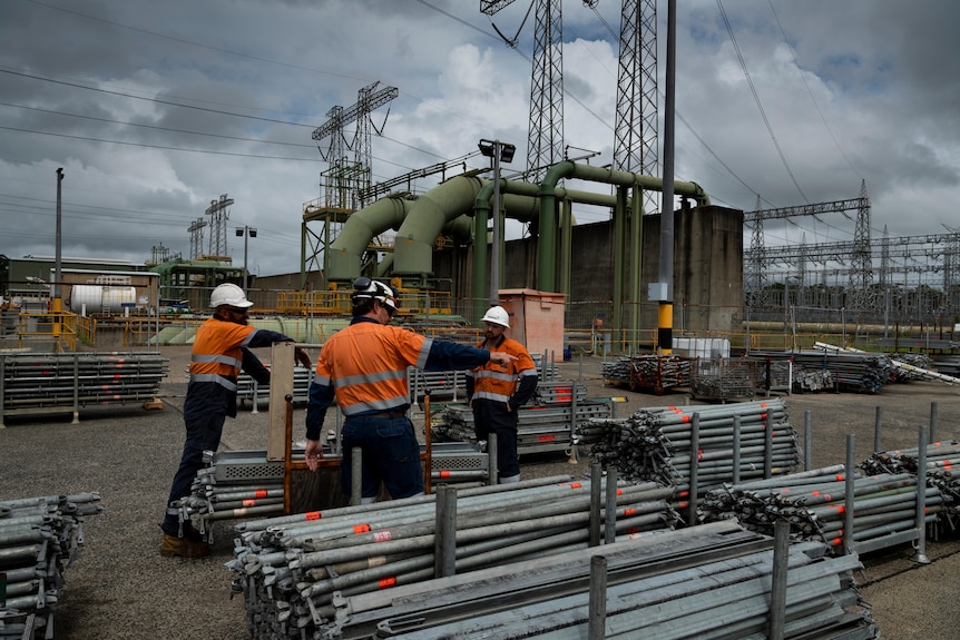 Men in hi-wis working over a pile of pipes