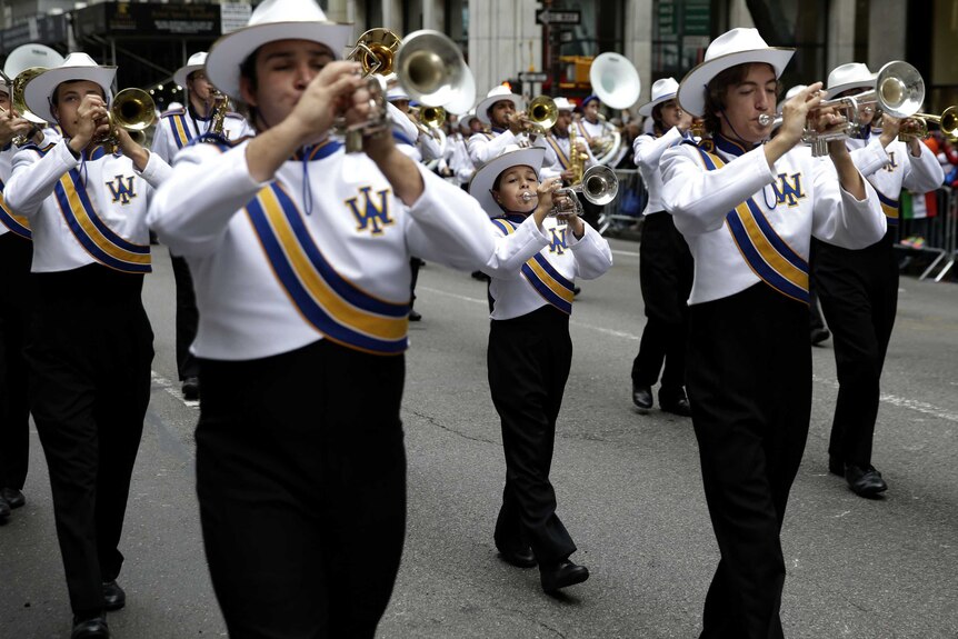 A band marches on the streets of New York playing trumpets.