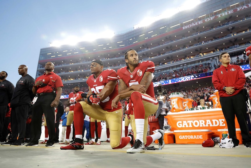 Two American football players – one of them Colin Kaepernick – kneeling down in protest at the start of a match.