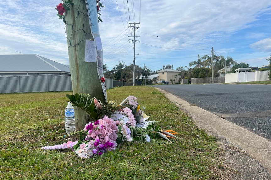 bunches of flowers left underneath a powerpole near the site where a teenager was fatally stabbed.  