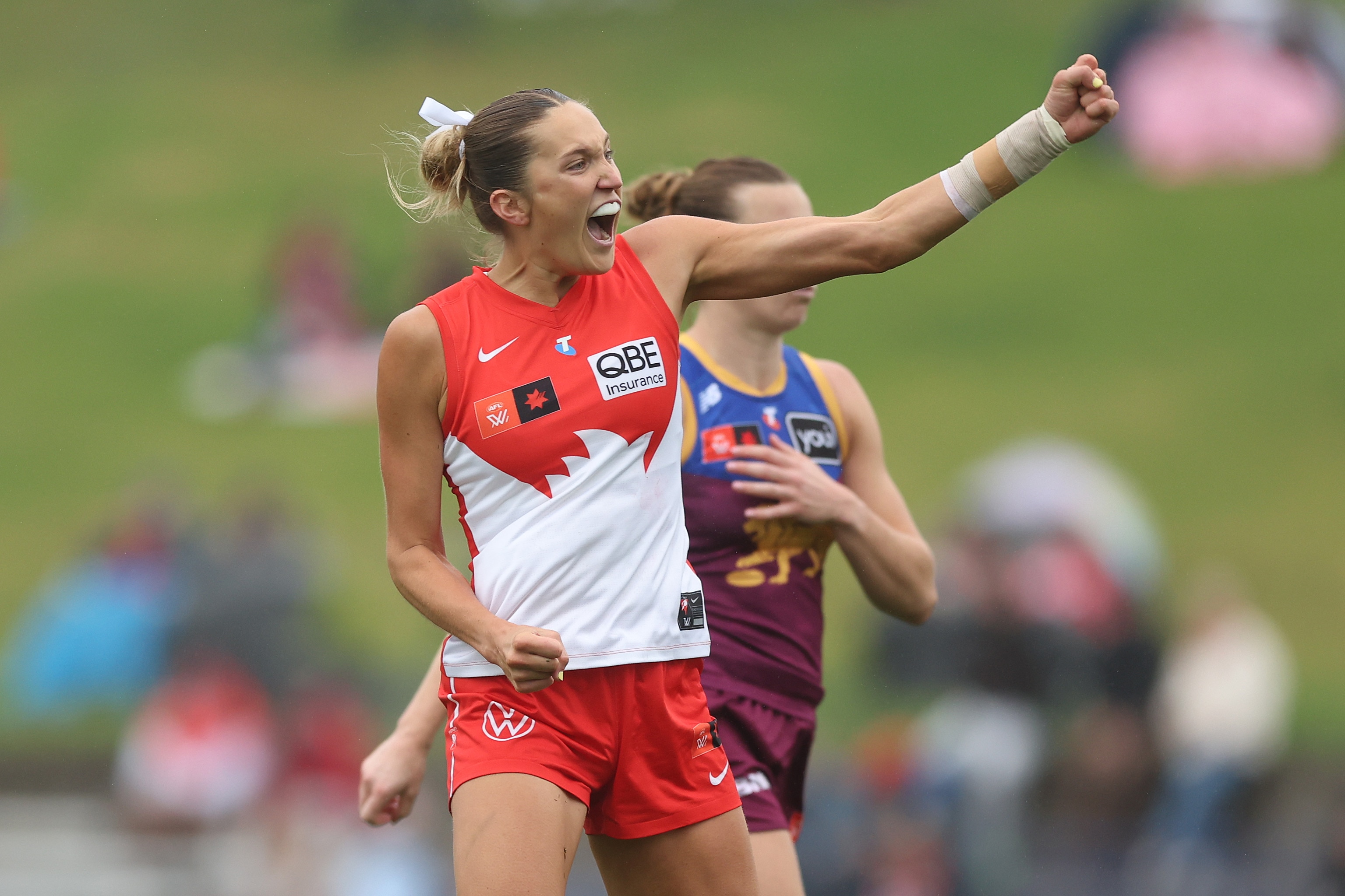 AFLW player yells and punches the air in celebation after kicking a goal
