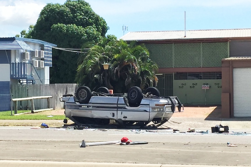 A mini-van upside down with its roof crushed.