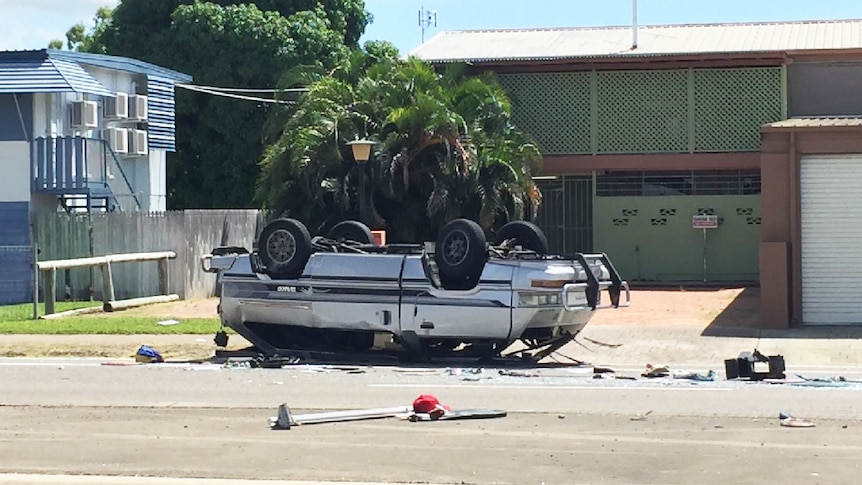 A mini-van upside down with its roof crushed.