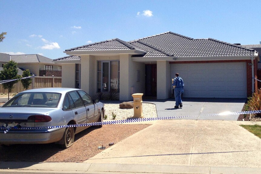 Forensic police walk towards a house in Point Cook after the discovery of a body there.