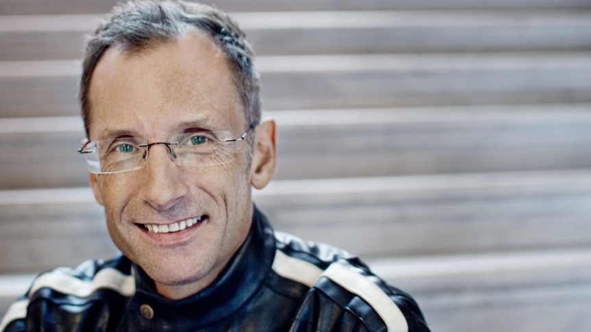 Close-up headshot of a man in glasses sitting on steps.