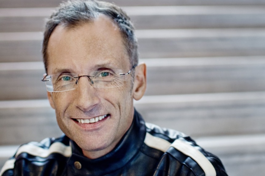 Close-up headshot of a man in glasses sitting on steps.