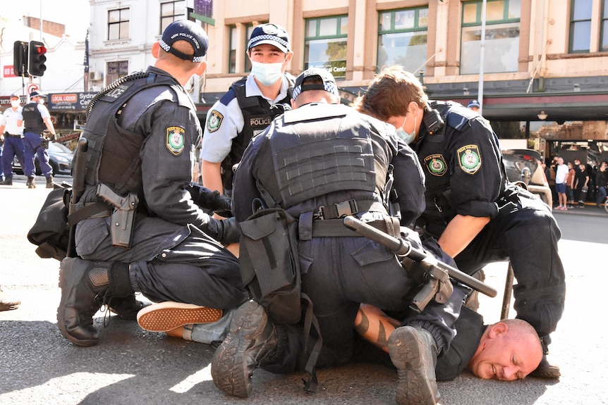 Several police officers holding a man on the ground.