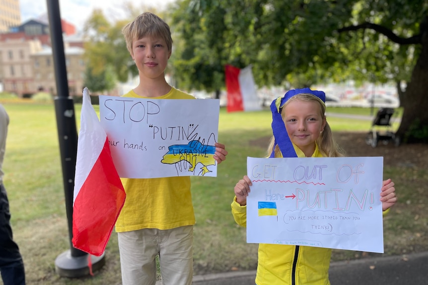 Two children holding banners to protest against Vladimir Putin.