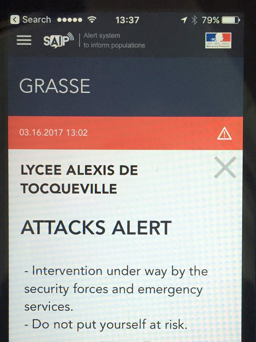 A French police message alert is displayed on a mobile phone, saying "attacks alert".