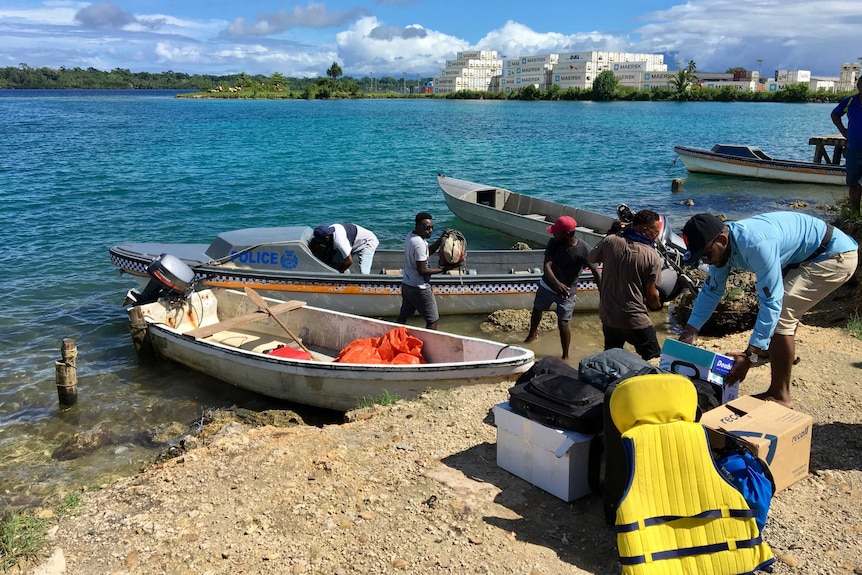 three boats on bank, with men off-loading supplies.