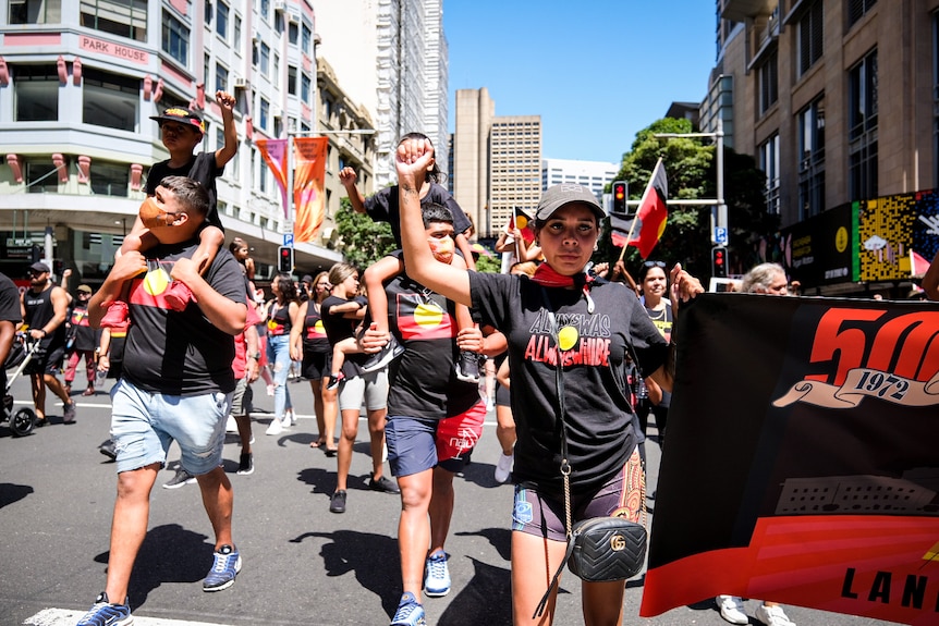 people marching in shirts with the indigenous flag