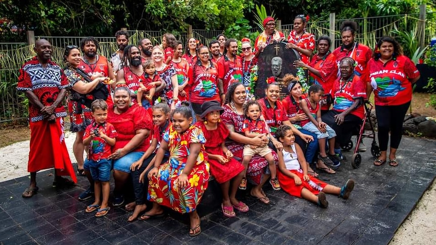 Group of people sitting around Eddie Mabo's head stone in Mer Island.