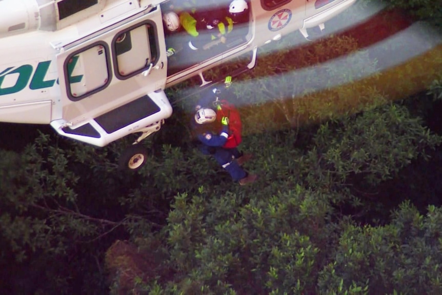 A paramedic on a winch under a helicopter