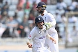 An English fielder roars in celebration as a wicketkeeper pats him on the shoulder during a Test in India.