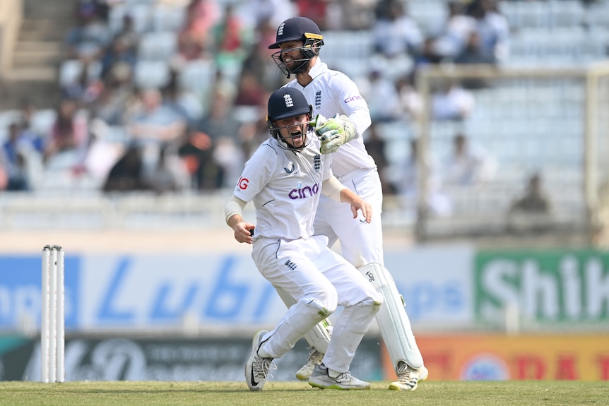 An English fielder roars in celebration as a wicketkeeper pats him on the shoulder during a Test in India.